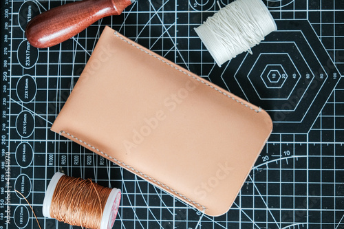 Vegetable tanned leather phone case craftmaship working with thread and tool photo