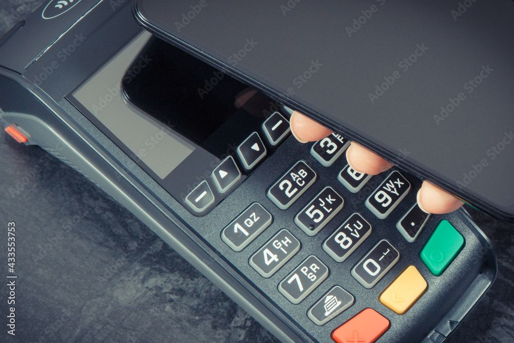 Hand of woman using payment terminal and smartphone to cashless paying. Finance concept Hand of woman using payment terminal and smartphone to cashless paying. Finance concept