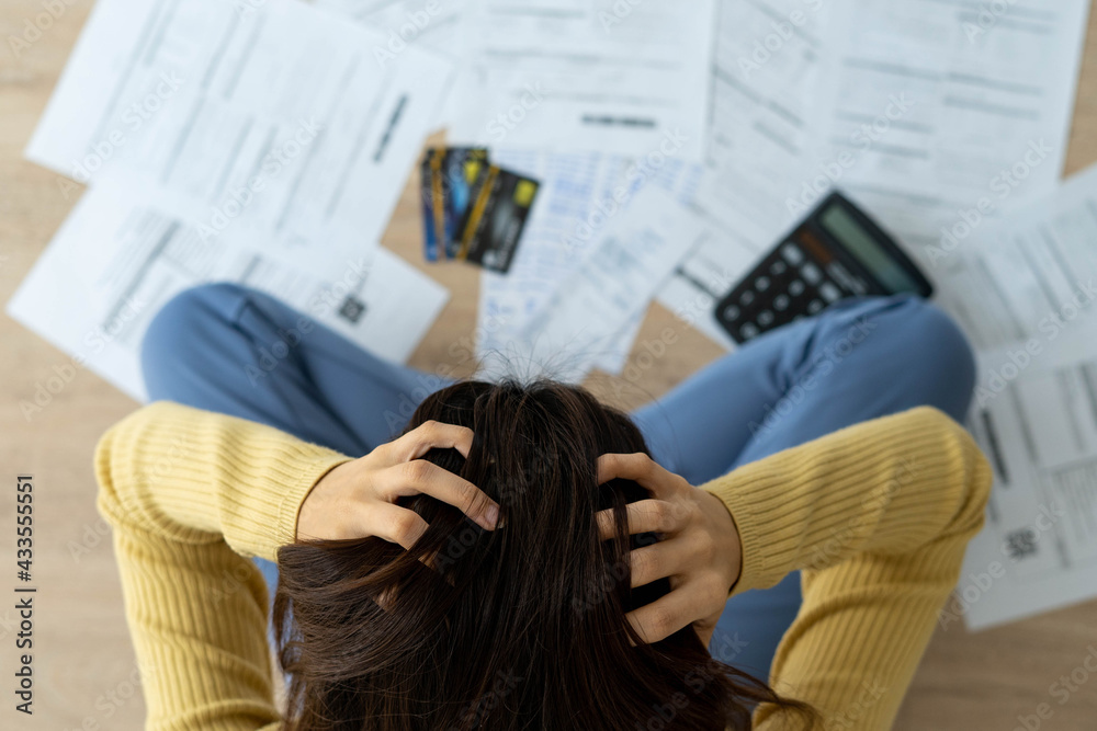 Women stress about a lot of credit card debt and bills on the floor. The housewife has trouble calculating monthly expenses and the budget is not enough to pay off the debt Women stress about a lot of credit card debt and bills on the floor. The housewife has trouble calculating monthly expenses and the budget is not enough to pay off the debt