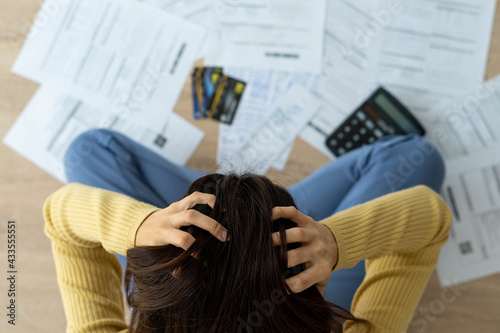 Women stress about a lot of credit card debt and bills on the floor. The housewife has trouble calculating monthly expenses and the budget is not enough to pay off the debt