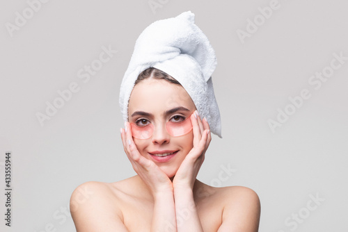 Woman applying eye patches. Portrait beauty girl with towel on head.