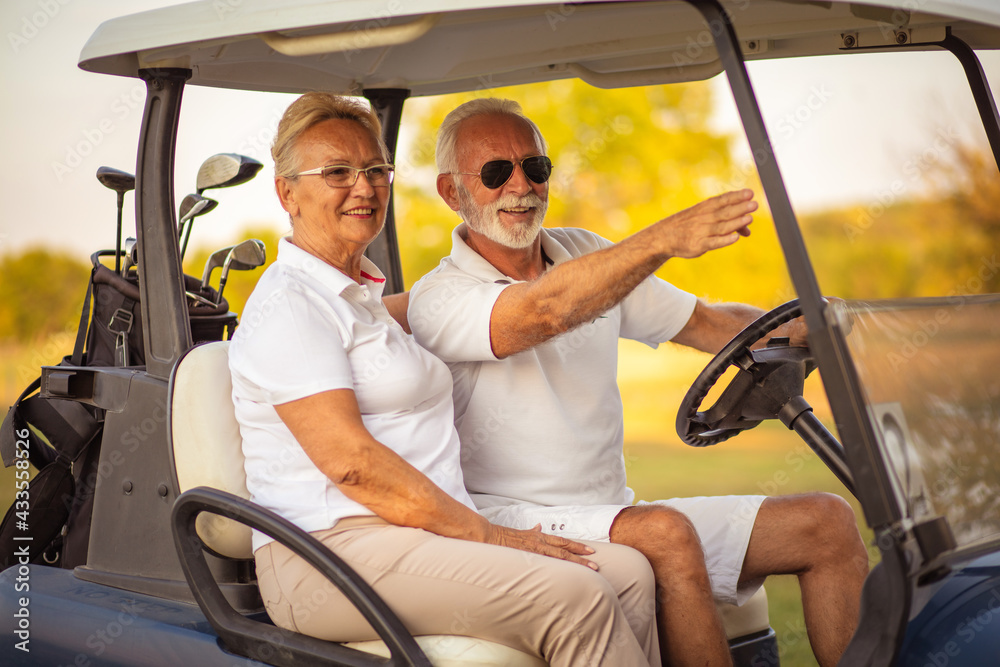 Elderly golf couple rides in a golf cart. Elderly golf couple rides in a golf cart.