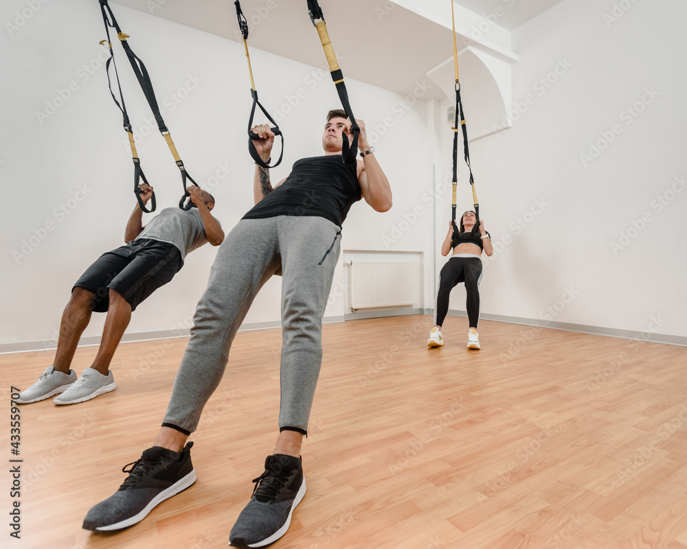 Athletic multinational people doing exercise with elastic rope in gym Athletic multinational people doing exercise with elastic rope in gym