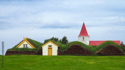 Glaumbaer scenic traditional village with red roof church  houses covered with turf and grass growing on the roof  Iceland  Europe