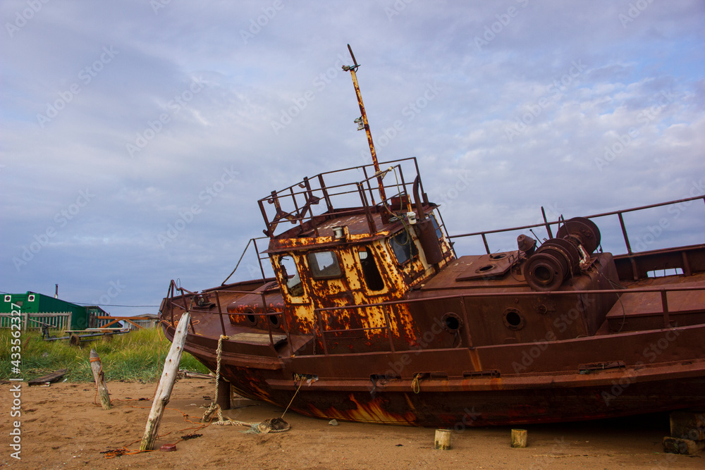 Fototapeta premium Ship graveyard. A sunken rusty abandoned fishing vessel in Russia, the Kola Peninsula, the Barents Sea, Teriberka.