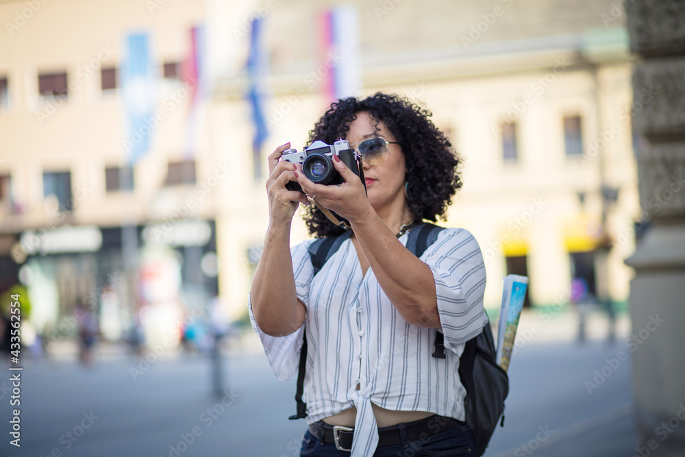 Woman in city holding vintage camera.