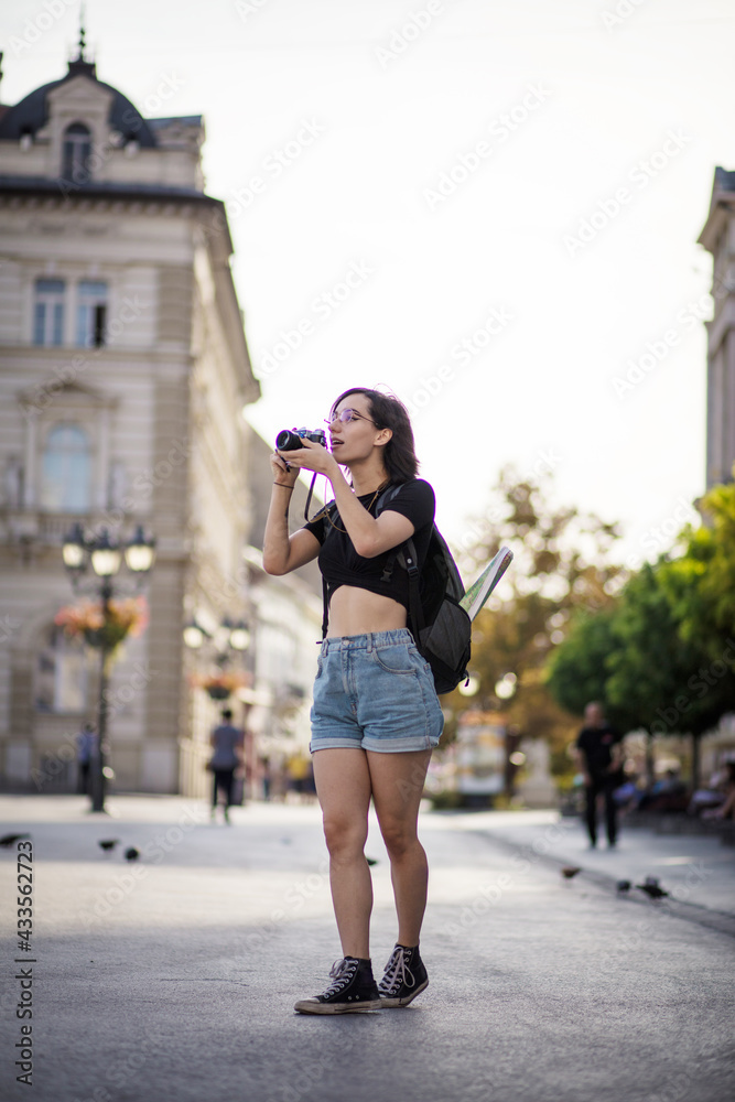 Young woman traveling single in Europe. Young woman taking photo in the city with camera.
