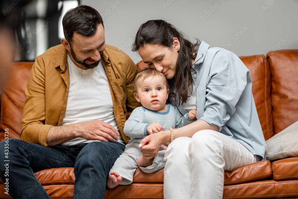 Happy father, mother and little son are playing on sofa in living room. Child care and parenting. Love and harmony in family relationships. Happy father, mother and little son are playing on sofa in living room. Child care and parenting. Love and harmony in family relationships.