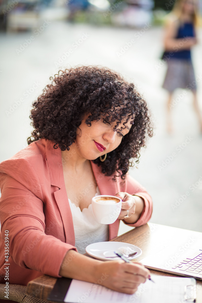 Business woman sitting in café writing on document. - obrazy, fototapety, plakaty 