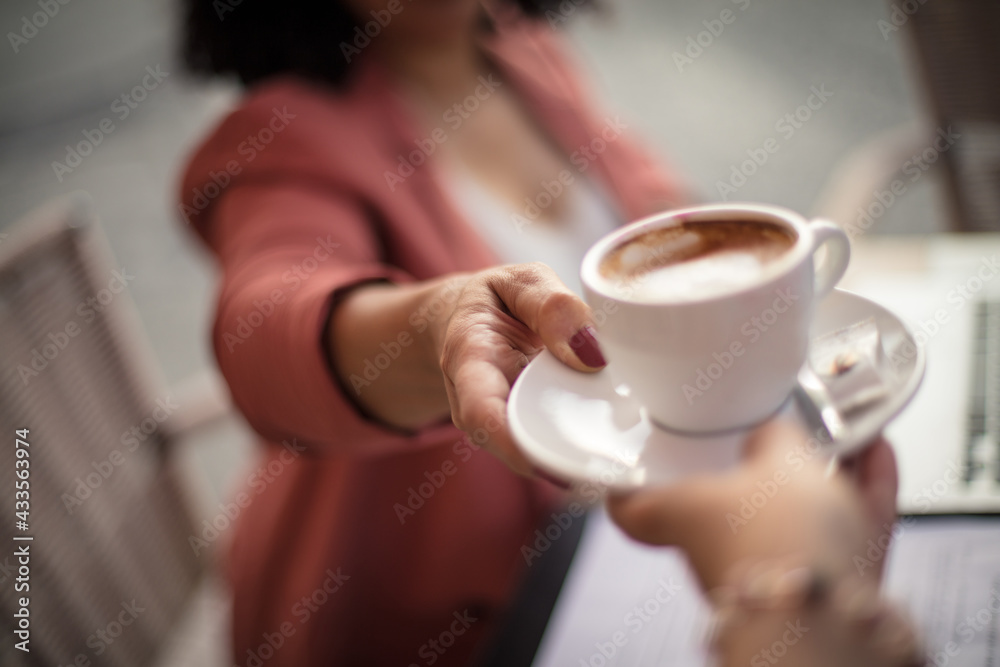 Woman at café taking mug of coffee. Focus is on hand. - obrazy, fototapety, plakaty 