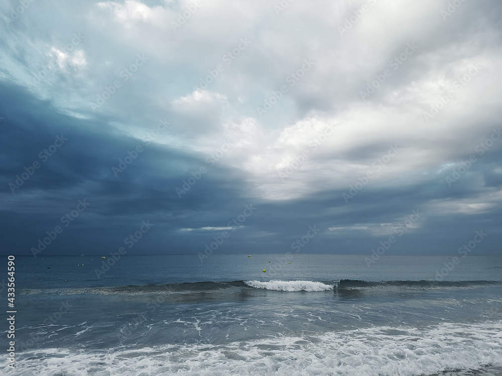 Sea view with traveling waves against the background of a dark sky with cumulus clouds.