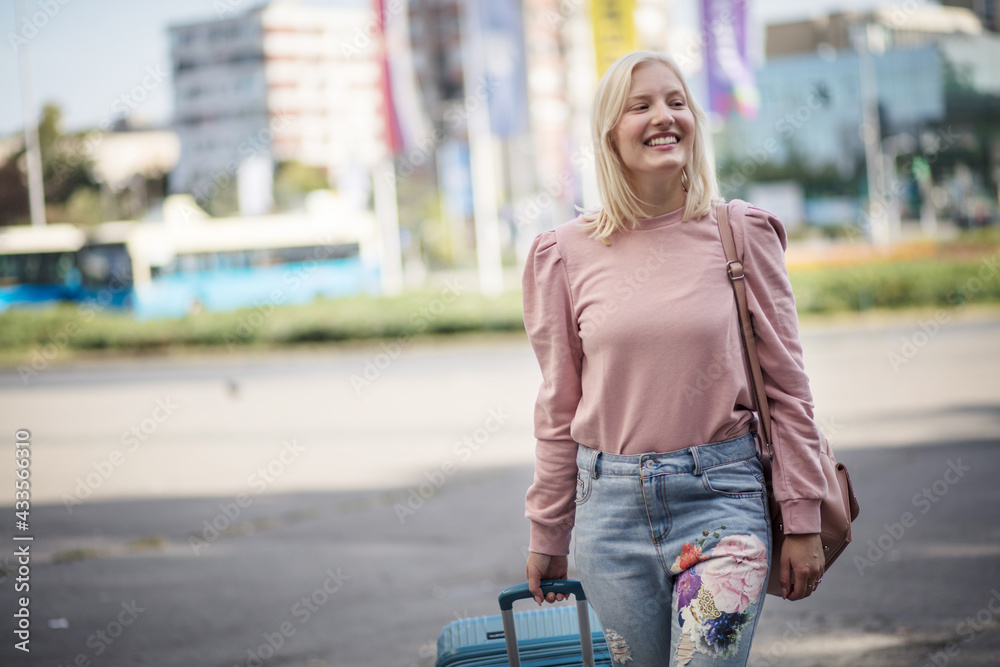 Smiling young woman with suitcase on the street. Leaving the city. Smiling young woman with suitcase on the street. Leaving the city.