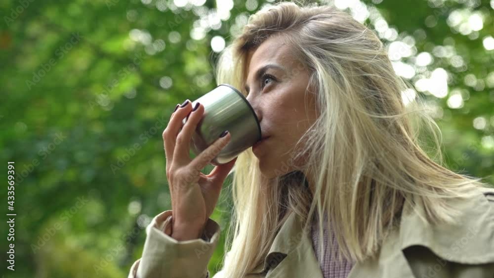 Attractive blonde woman walk in at sunny day and drink coffee or tea. Attractive blonde woman walk in at sunny day and drink coffee or tea.