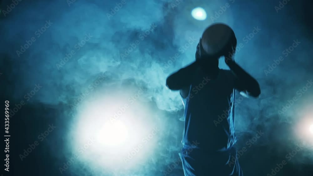 Slow motion of a sportsman throwing a basketball in the dark Slow motion of a sportsman throwing a basketball in the dark