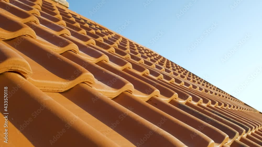Overlapping rows of yellow ceramic roofing tiles covering residential building roof.