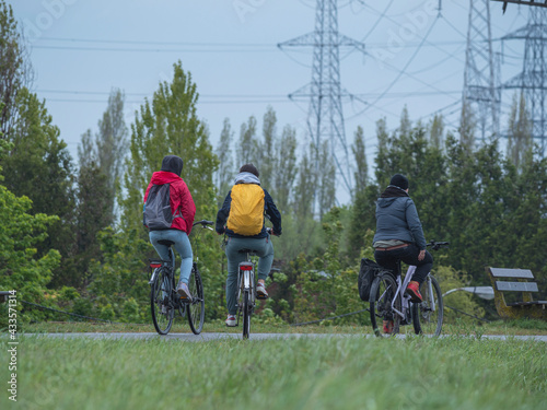 Fototapeta Naklejka Na Ścianę i Meble -  Three friends on bicycles in rain gear on a rainy day