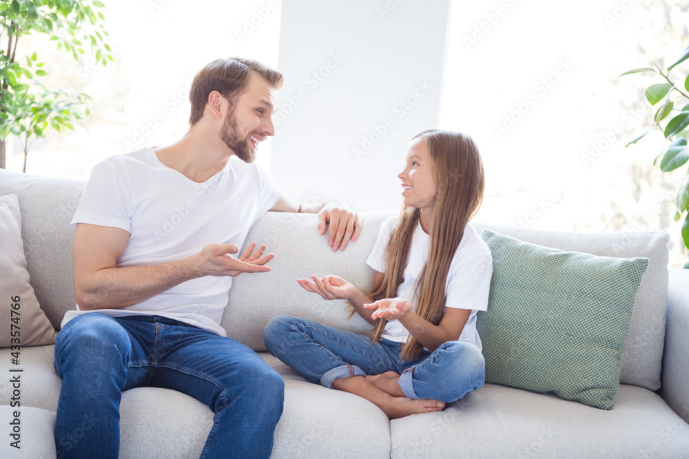 Photo of charming cute father daughter dressed casual clothes sitting couch discussing last news indoors house apartment