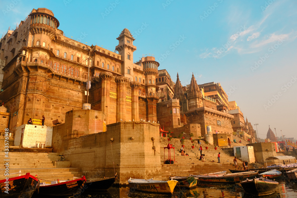 India, Varanasi Ganges river ghat with ancient city architecture as viewed from a boat on the river at sunset.