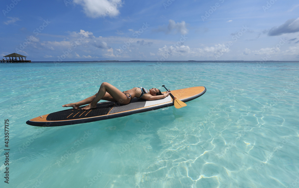 girl in bikini lies on Surfboard in the ocean, Maldives