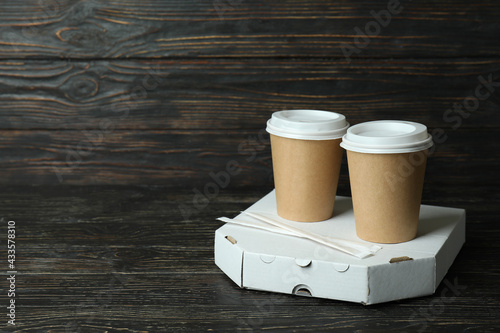 Pizza box and paper cups on wooden background