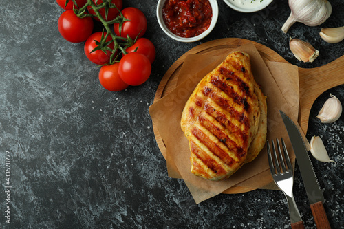 Concept of tasty eating with grilled chicken on black smokey background