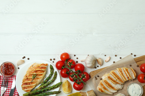 Concept of tasty eating with grilled chicken on white wooden table