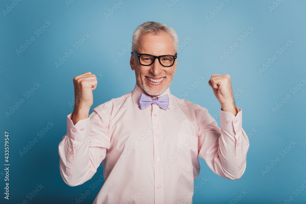 Photo of aged good mood guy raise fists winner concept isolated on blue background Photo of aged good mood guy raise fists winner concept isolated on blue background