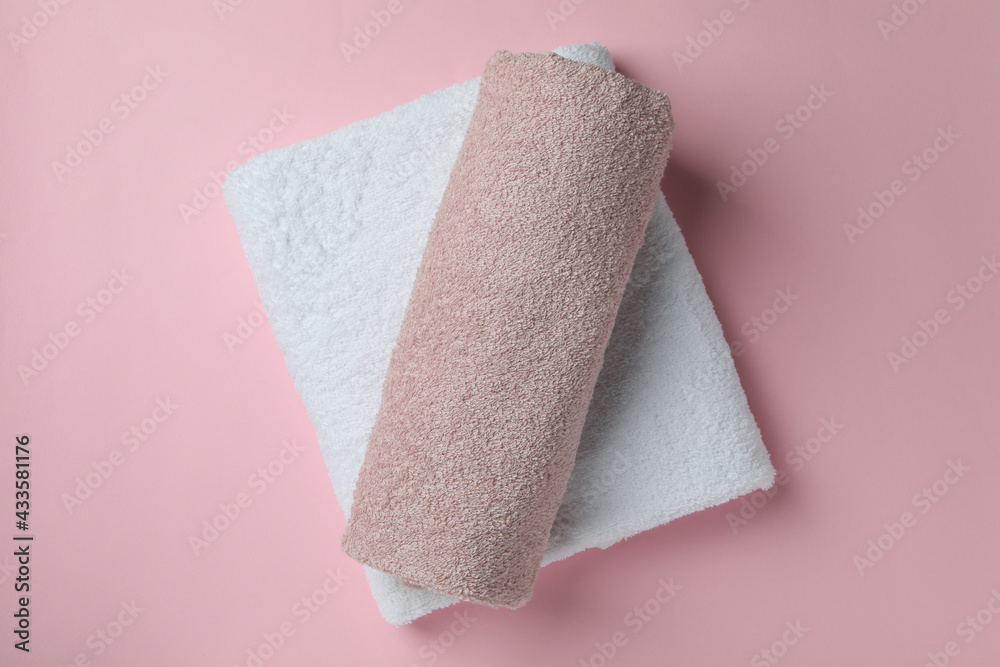 Clean folded towels on pink background, top view