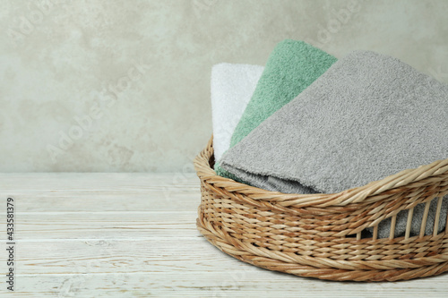 Basket with clean towels on white wooden table