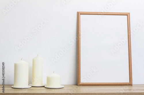 A mock up photo frame with candle light on table over the white wall. 