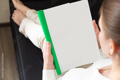 Woman holding brochure with blank cover on wooden background, top view. Mock up for design