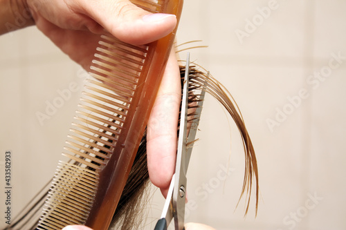 Hand of hairdresser cuts hair of woman close up in beauty salon.