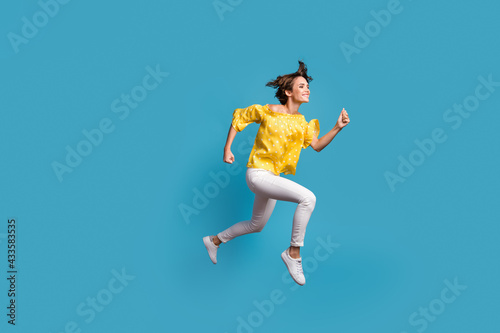 Full size profile side photo of attractive lady jump up air run empty space smile isolated on blue color background © deagreez