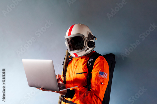 Quadro em tela Astronaut in spacesuit works on laptop, High-tech space exploration concept
