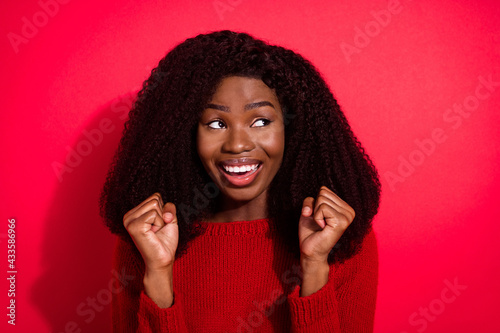 Photo of young afro woman happy positive smile rejoice victory fists hands lucky look empty space isolated over red color background © deagreez