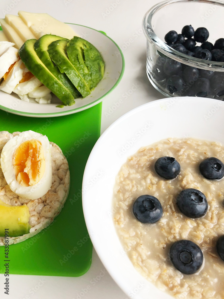 delicious breakfast consisting of porridge served with blueberries and fitness toast with egg and avocado