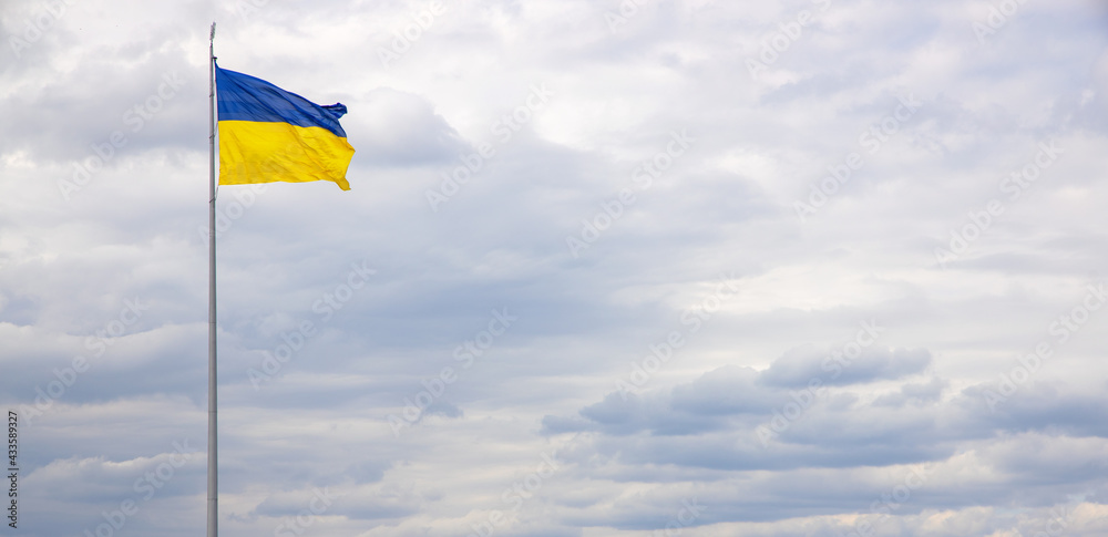 Ukraine national flag against a blue sky. Banner for text about the freedom and independence of country. Ukraine national flag against a blue sky. Banner for text about the freedom and independence of country.