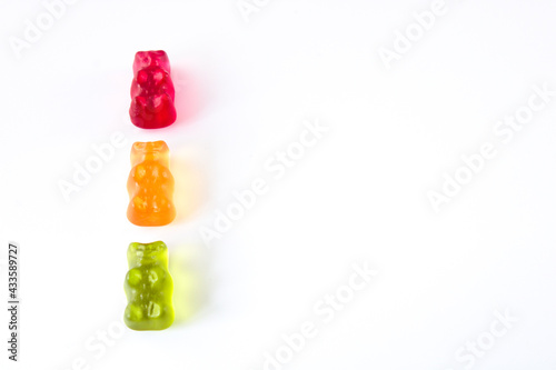 Three gummy bears in colours of traffic lights lined up vertically, isolated on white background with copy space