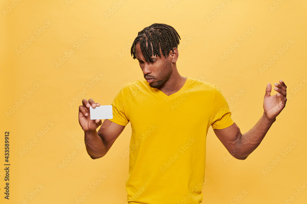 Handsome Afro Man Posing Over Yellow Background wearing yellow T-shirt keeping mock up credit card Handsome Afro Man Posing Over Yellow Background wearing yellow T-shirt keeping mock up credit card