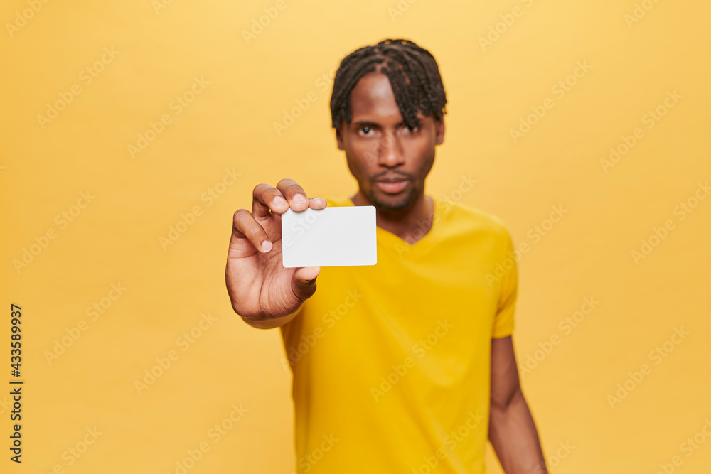 Handsome Afro Man Posing Over Yellow Background wearing yellow T-shirt keeping mock up credit card