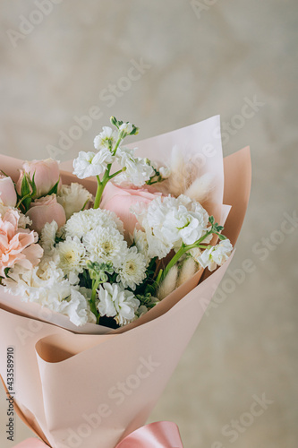 Bouquet of white freesias, carnations and chrysanthemums with pink roses and carnations in a pink package with a ribbon. Summer background