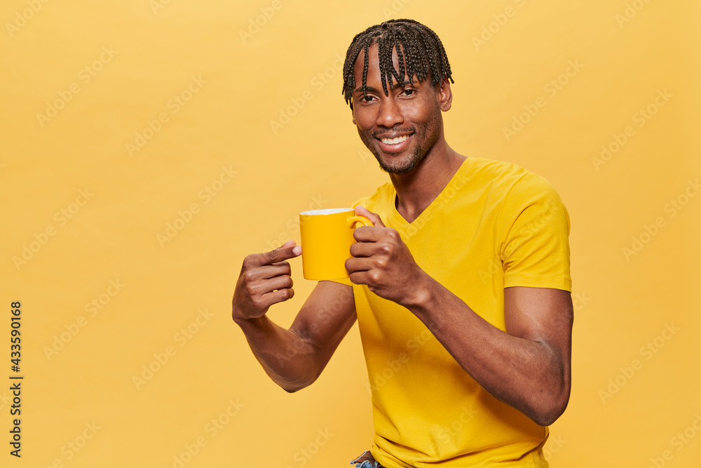 Handsome Afro Man Posing Over Yellow Background wearing yellow T-shirt and yellow cup 