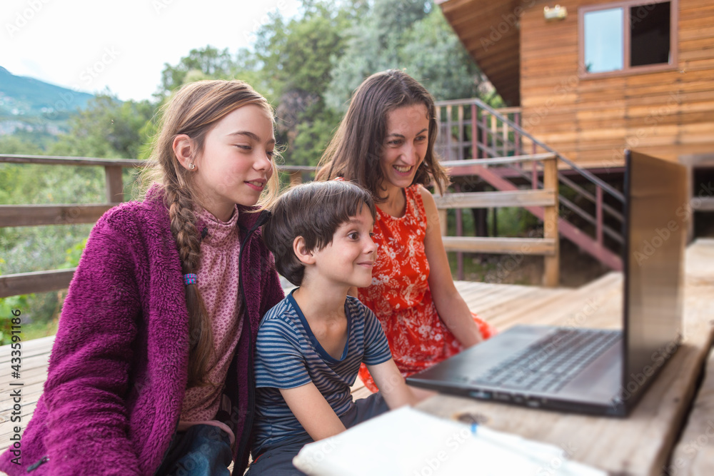 A woman and children look at a laptop screen, communication at a distance A woman and children look at a laptop screen, communication at a distance