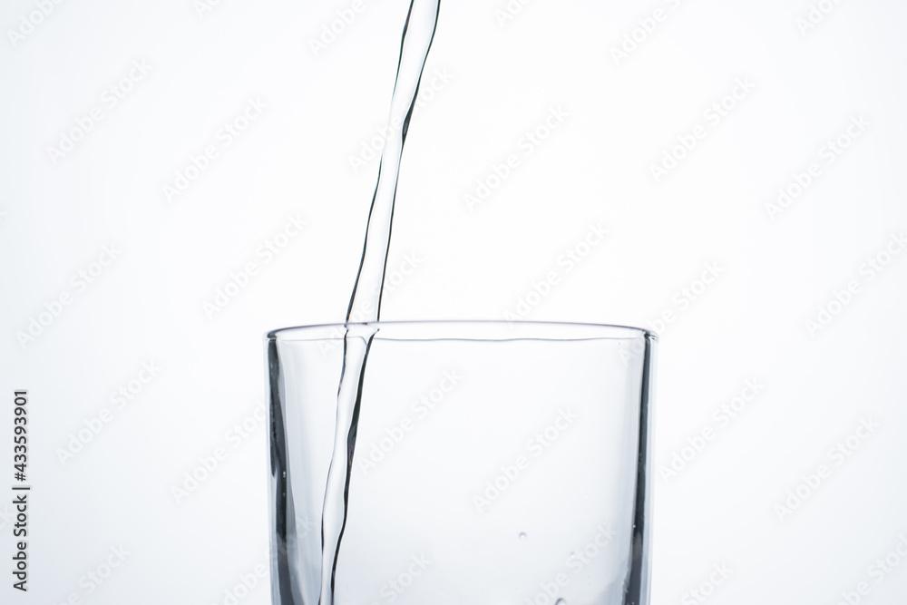 Jet of water or alcohol is pouring into a glass with splashes and bubbles, copy space Jet of water or alcohol is pouring into a glass with splashes and bubbles, copy space