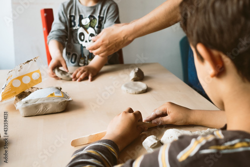 child playing with clay at home during quarantine. focused boy creating shapes with hands and using creativity and manual skills to mold toy shapes