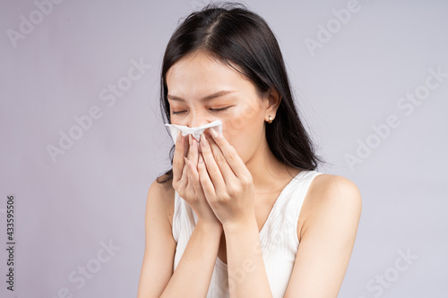 Asian woman sneezes when she has a cold