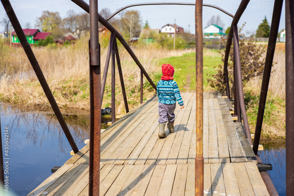 a boy walks on a bridge over the river, early spring a boy walks on a bridge over the river, early spring