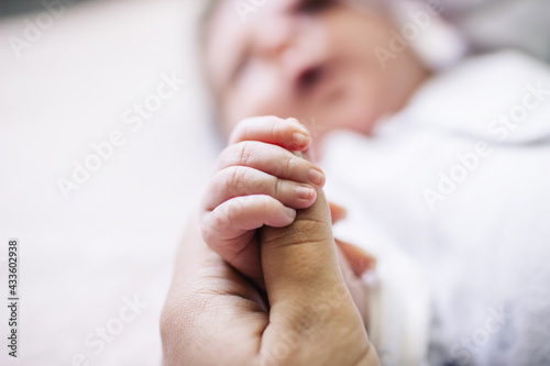 Mom holds her newborn baby by the hand