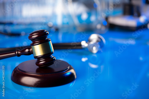 Medical law concept. Gavel and stethoscope on the glass table. Blue light.
