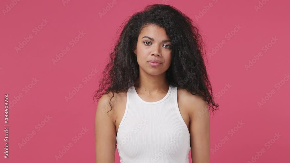 Smiling good surprised young african woman curly hair 20s years old wears white tank top shirt ask who me oh it so sweet put hands on chest isolated on dark pink color wall background studio portrait Smiling good surprised young african woman curly hair 20s years old wears white tank top shirt ask who me oh it so sweet put hands on chest isolated on dark pink color wall background studio portrait